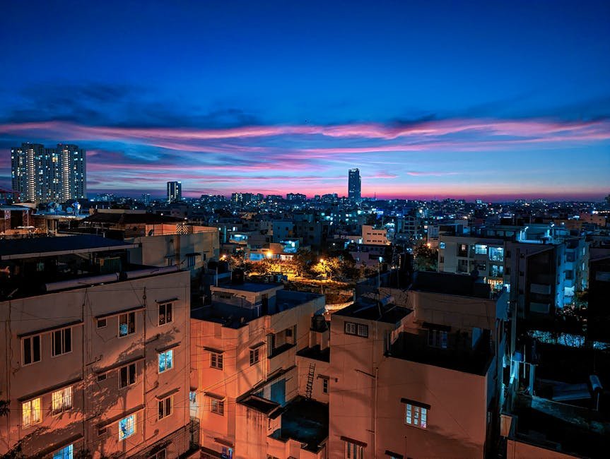 Stunning view of Bengaluru cityscape illuminated at dusk, showcasing modern architecture under a vivid sunset sky.